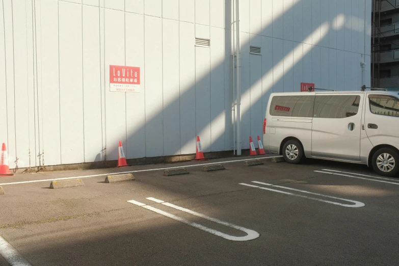 a white van parked in a parking lot with orange cones