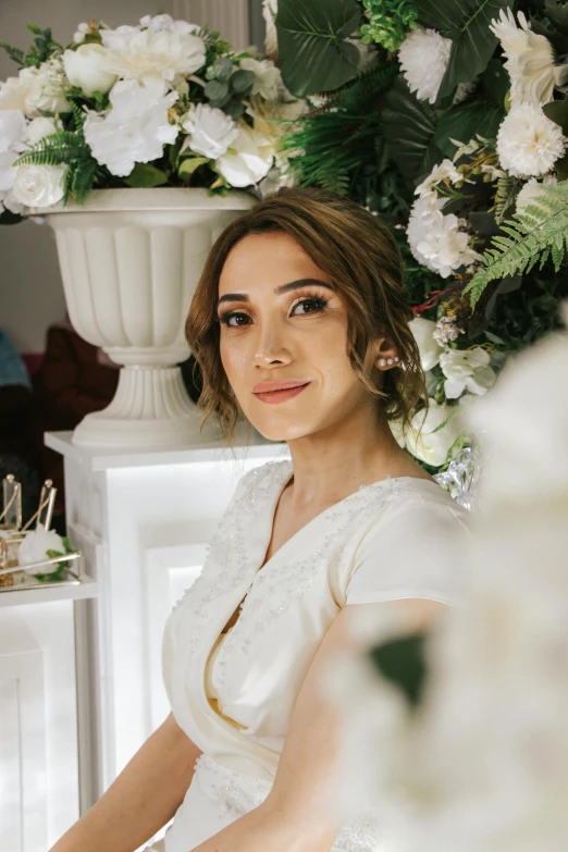 a woman in a white dress standing by some flowers