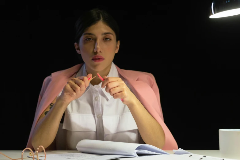 a young woman sitting in front of a desk with a lamp