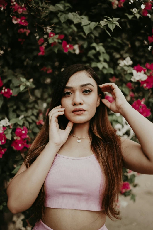 a pregnant woman posing near flowers talking on a cellphone