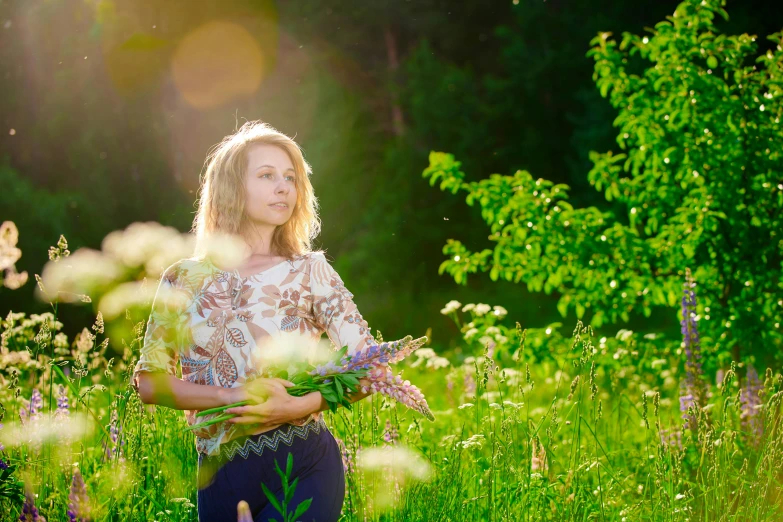 a woman is holding flowers in the grass