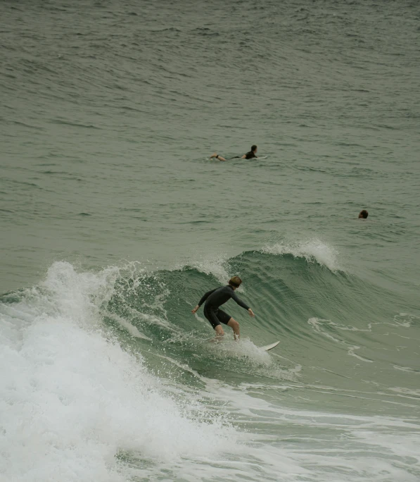 surfers in the ocean catching a small wave