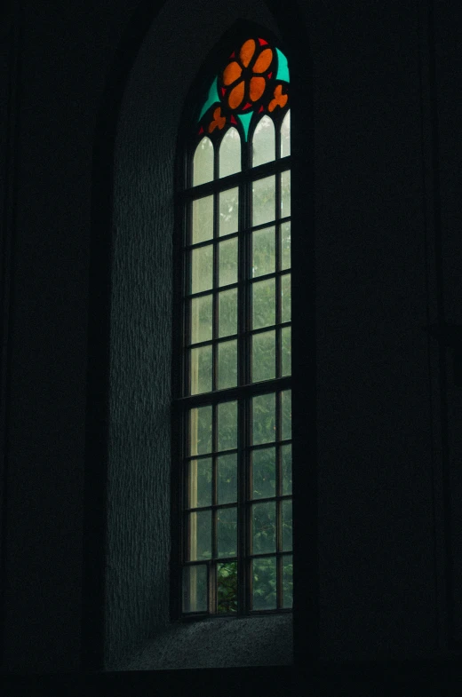 the stained glass window is in front of the dark wall
