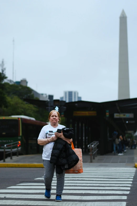 the woman carries a bunch of black bags down the street