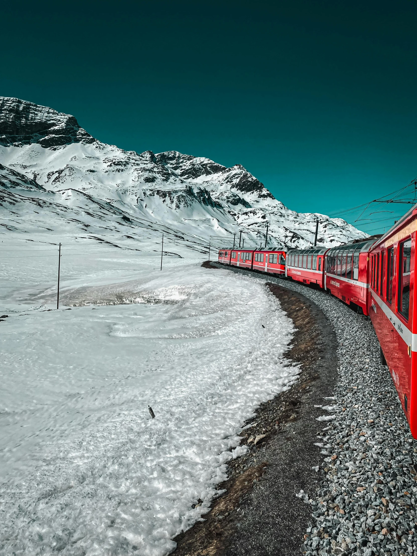 an orange train travels on a snowy hill side