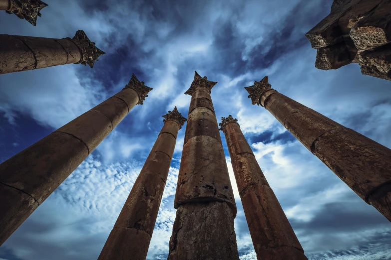 a group of tall pillars sit in the middle of a blue sky