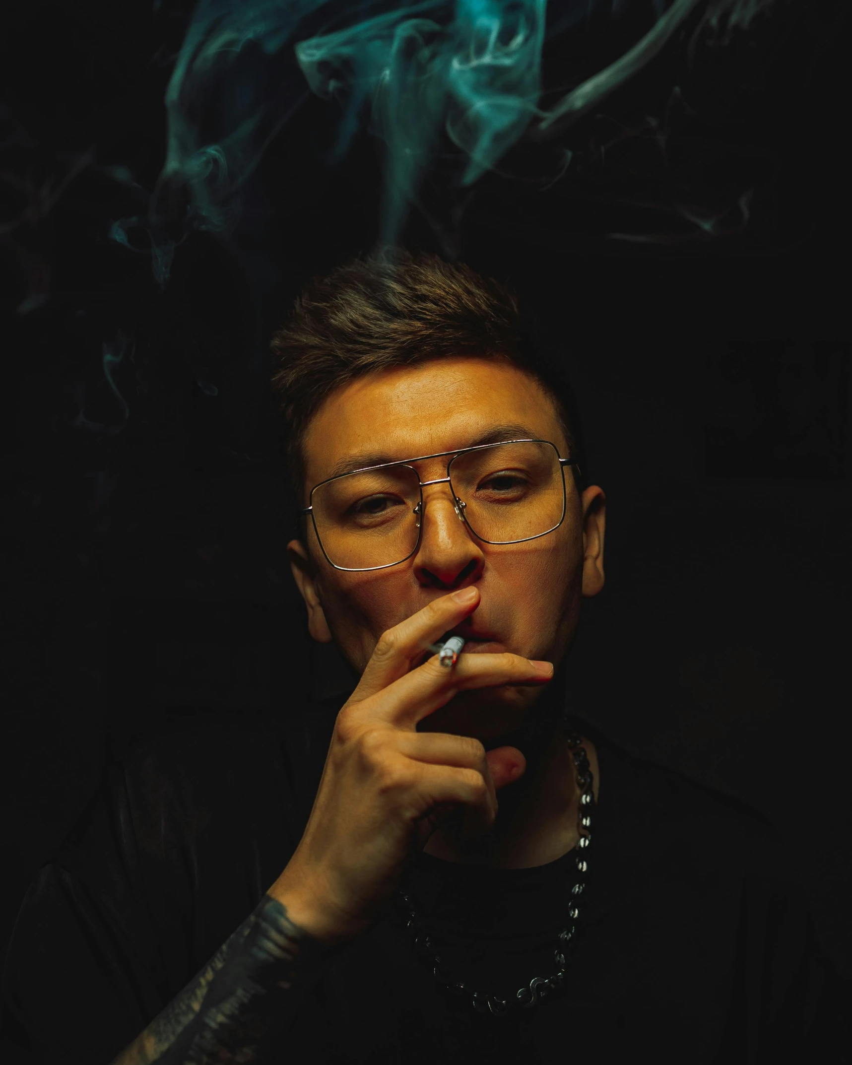 a young man with glasses on smoking a cigarette