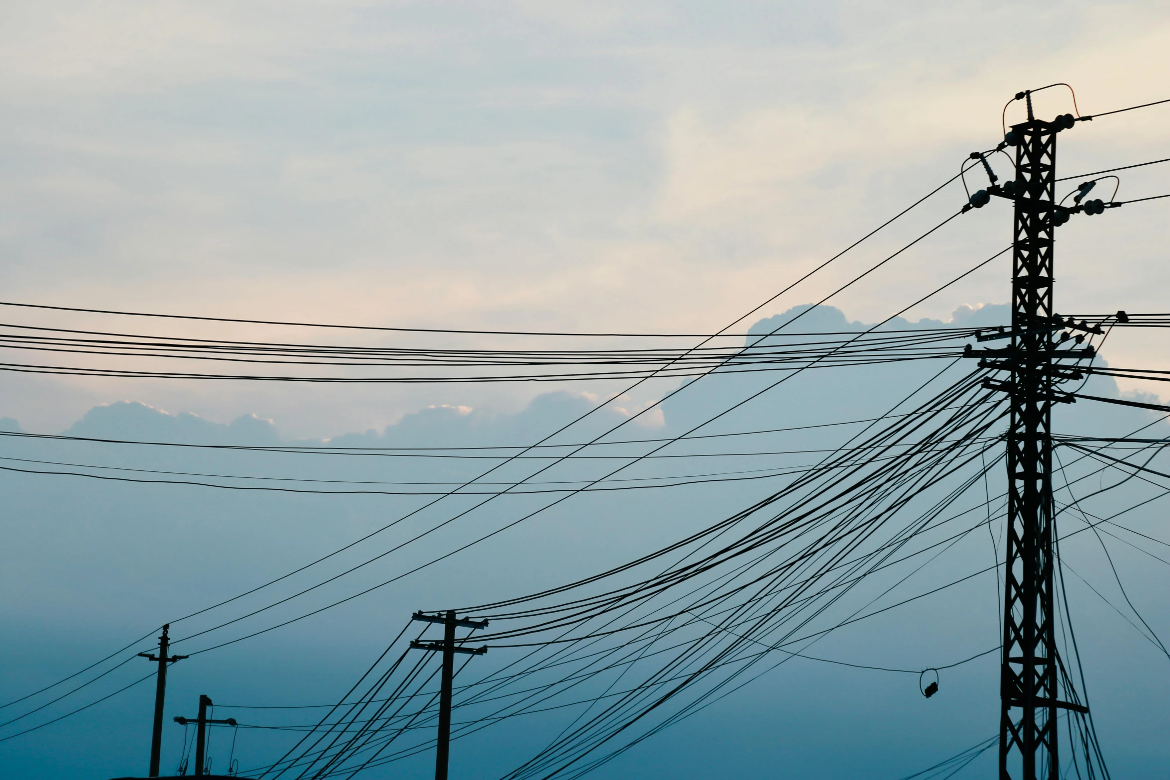 there is power lines and high - wire cables with cloudy sky