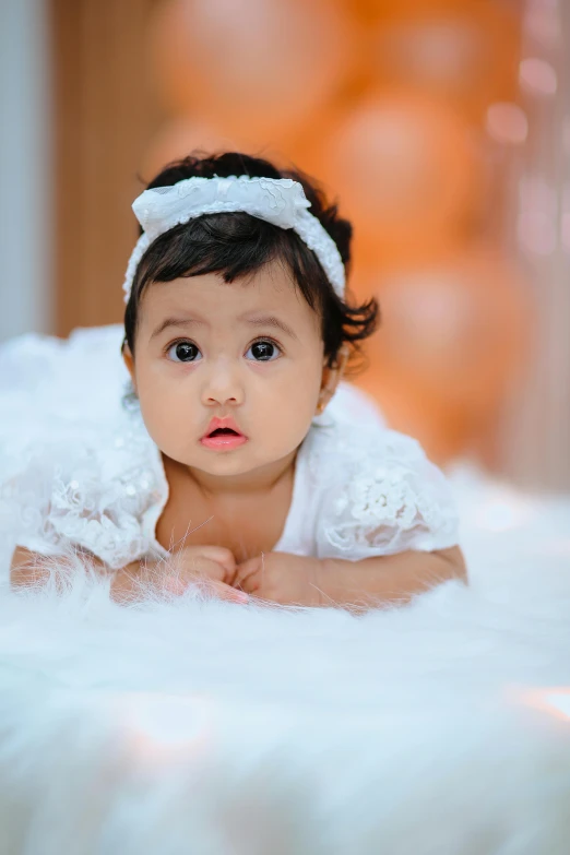 a baby laying on the floor in a dress