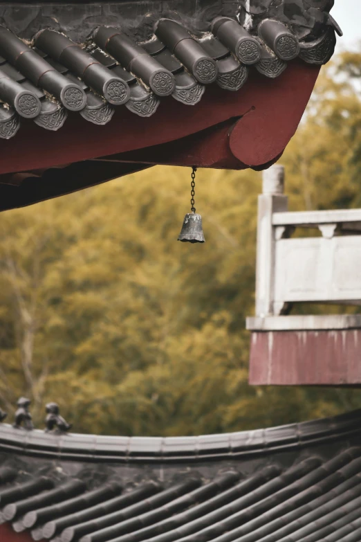 a bell hanging from a red roof with wooden railings