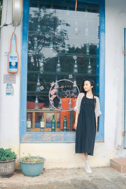 a girl standing in front of a window with bottles