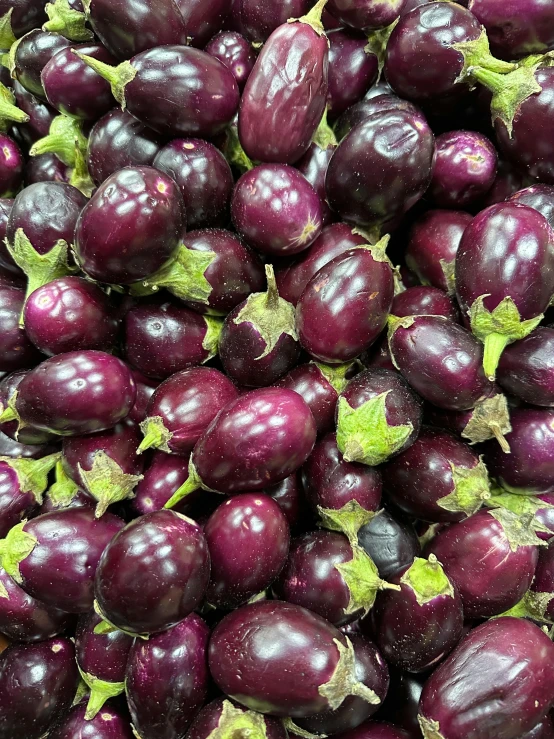 many purple fruits, including plums, are piled together