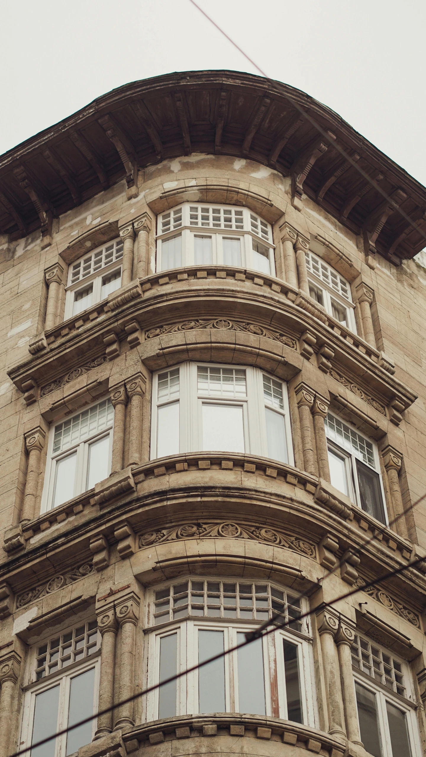 a tall tan building with many windows and some wires