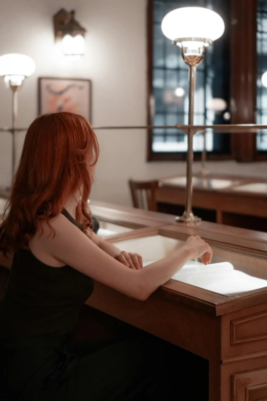 a young lady sitting at a table writing a book