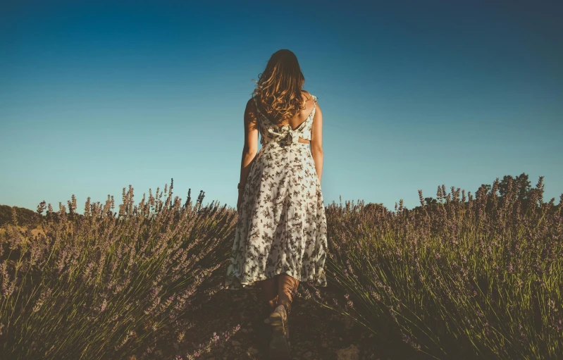 a girl is in a dress walking down a hill