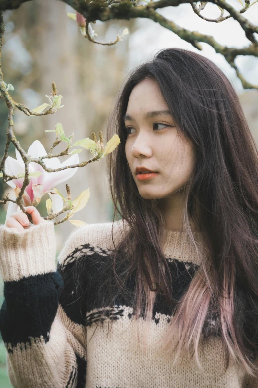 an asian woman holds a nch with small flowers in it