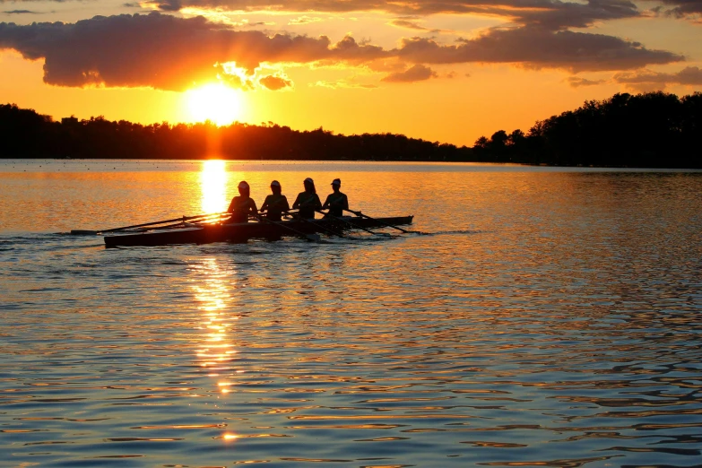 the rowers are rowing on the water at sunset