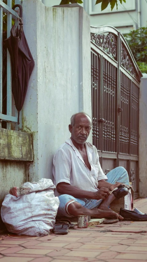 a man sitting on the sidewalk next to a doorway