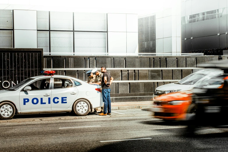 two police cars on a road by a wall