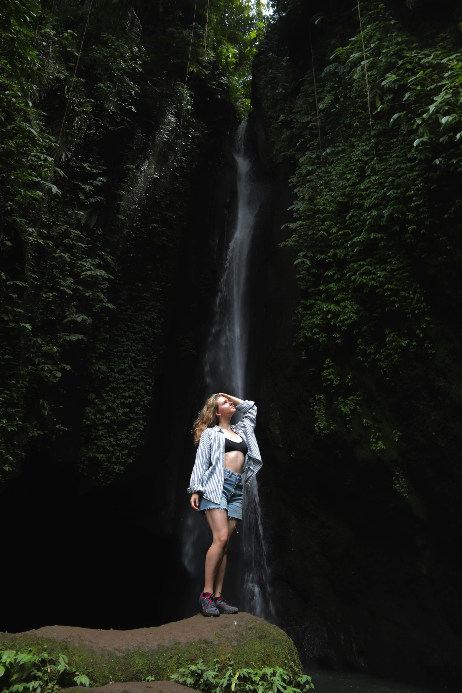 a woman standing in front of a waterfall