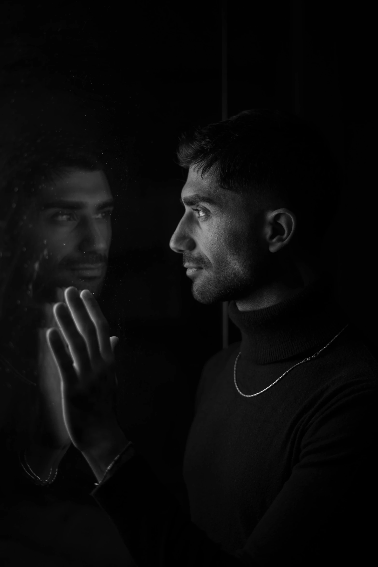 a man in the dark and praying behind a glass door