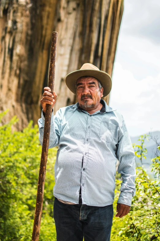 man with stick standing in front of rock formation