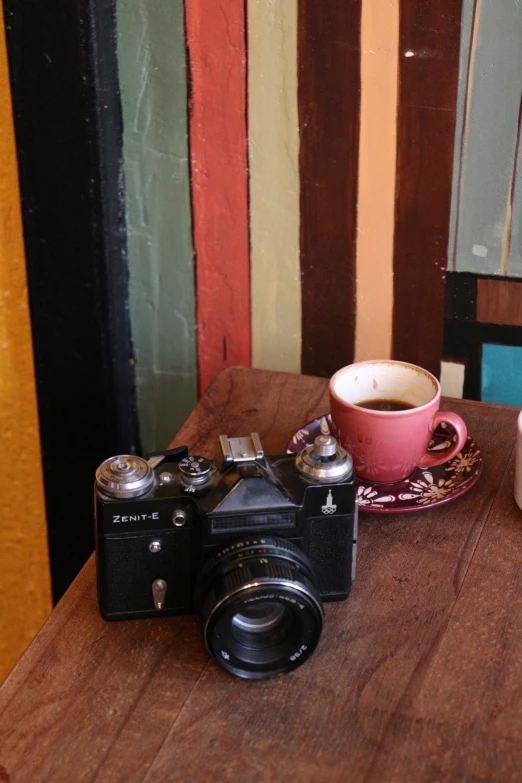 a camera sitting on top of a table next to a coffee cup