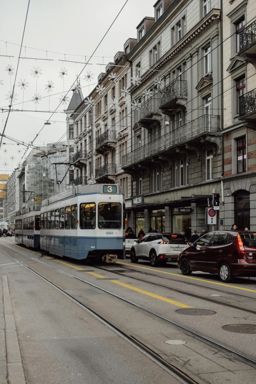 a passenger train on a city street next to tall buildings