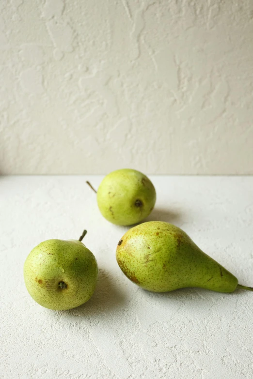 a group of three green pears sitting on top of a table