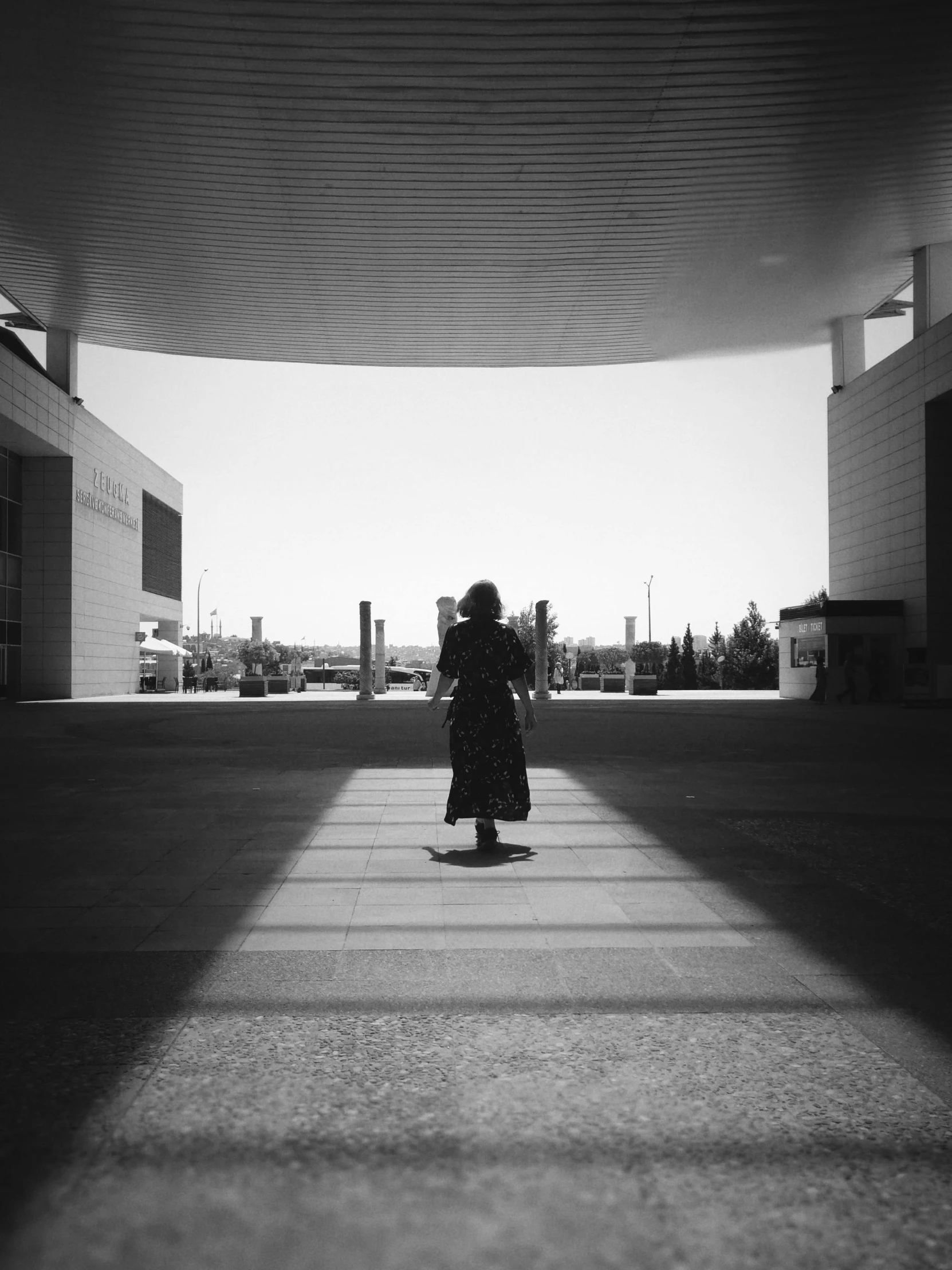 a woman walking down the sidewalk in black and white