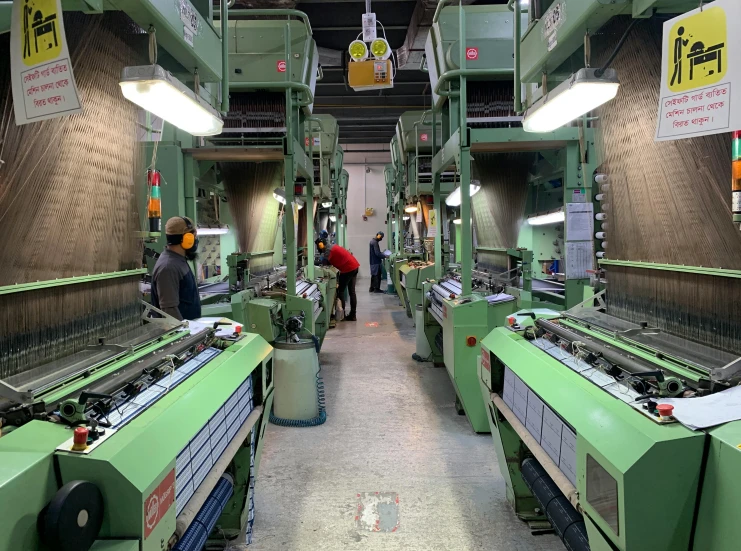 people look at sewing machines and tables in a factory