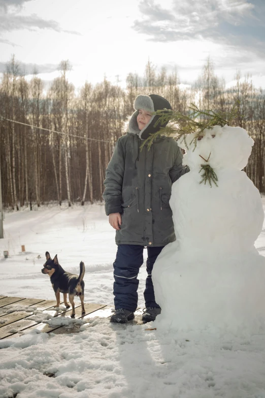 a man that is standing in the snow next to a snow man