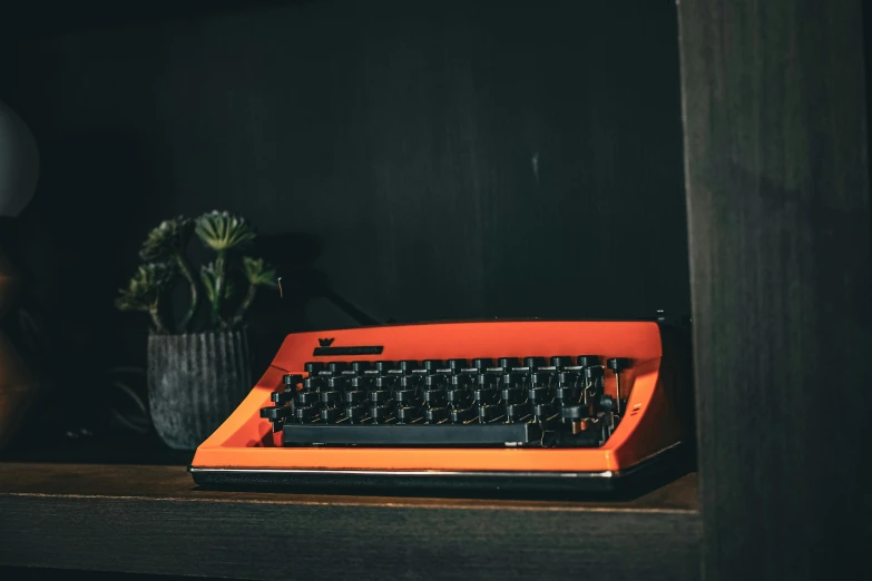 a red typewriter on top of a wooden table