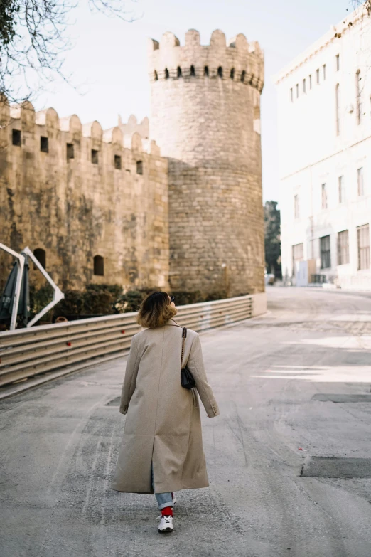 a woman walking in an old castle like area with a coat