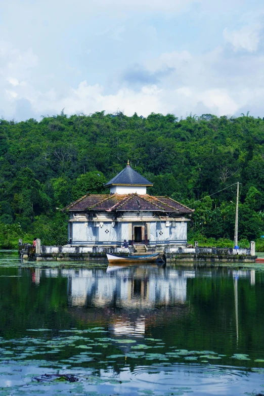 a house is shown in front of water with many trees around it