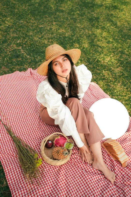 a woman sitting on top of a picnic cloth