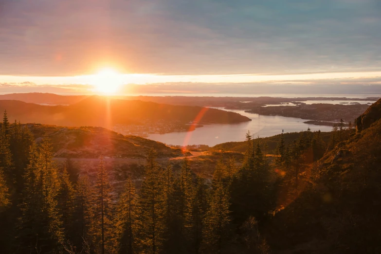 sun going down over a valley and some trees