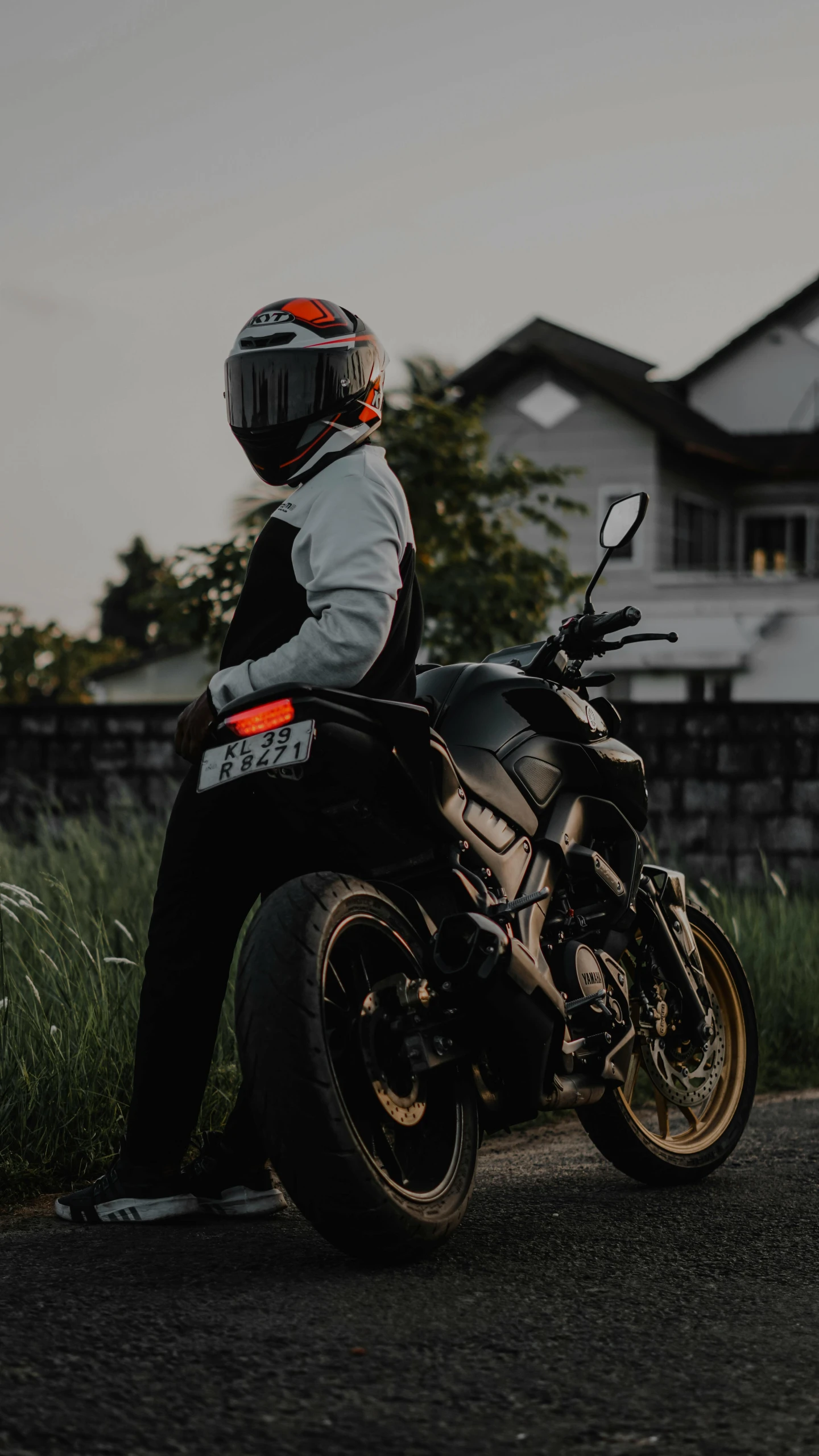 a person sitting on a motorcycle with grass next to it