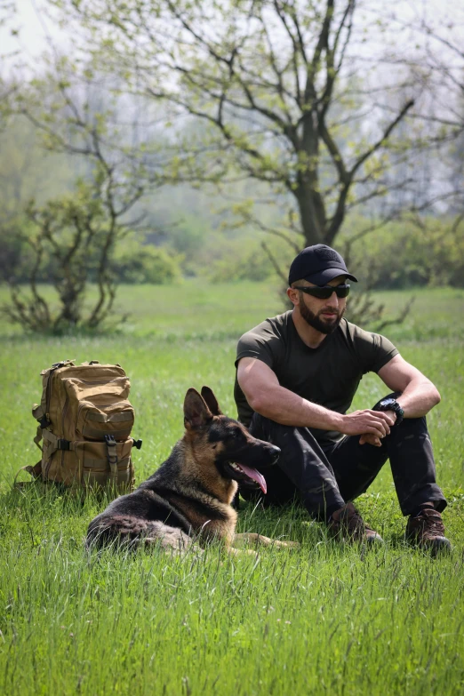 a man and his german shepard in a field with some suitcases