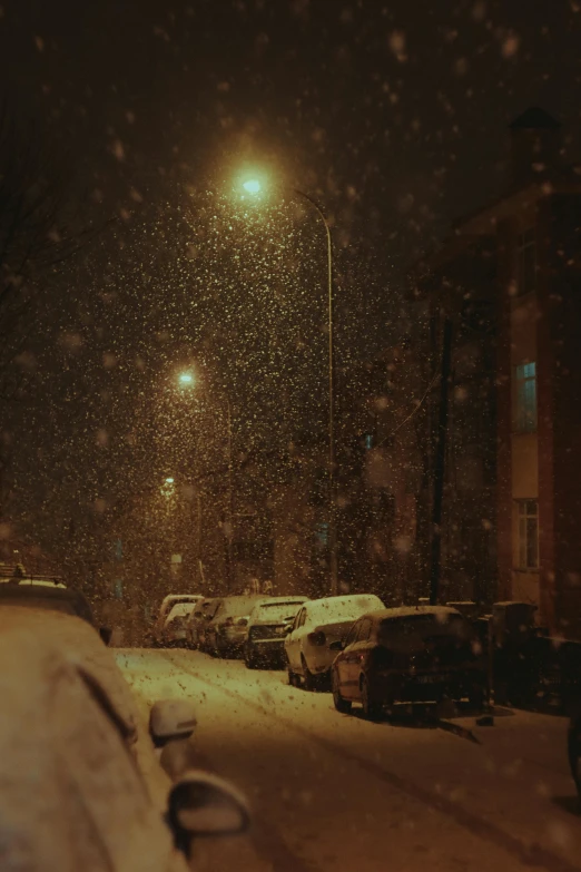 snowy street at night with cars covered in snow