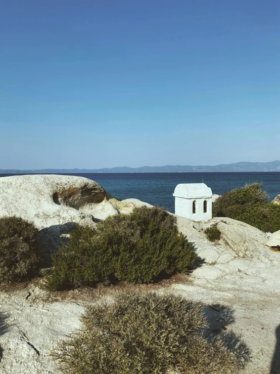 a white building on the shoreline with a blue sky in the background