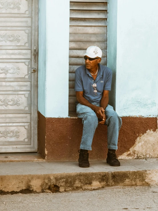 a man sitting on the curb in front of a blue building