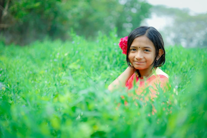 the little girl is sitting in the grass