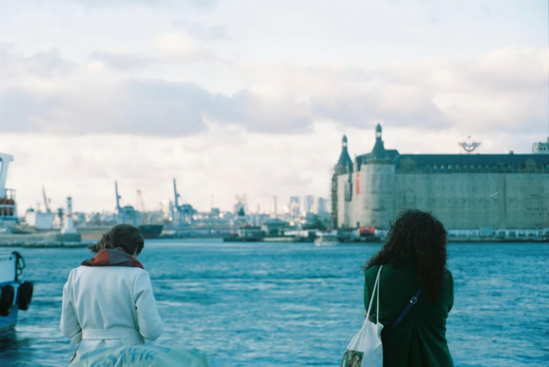 two people that are walking in front of a body of water