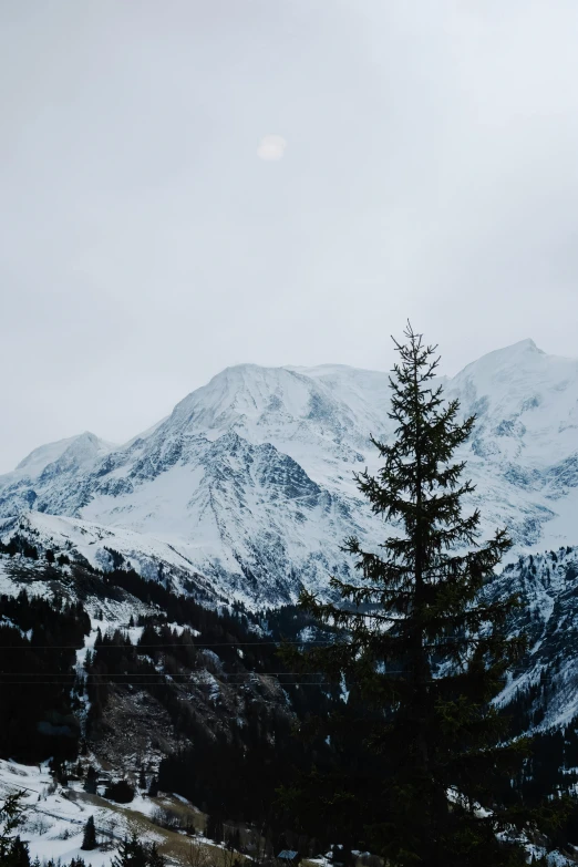 a view of a snowy mountain range with the moon in the distance