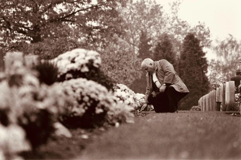 an elderly woman kneeling in front of graves