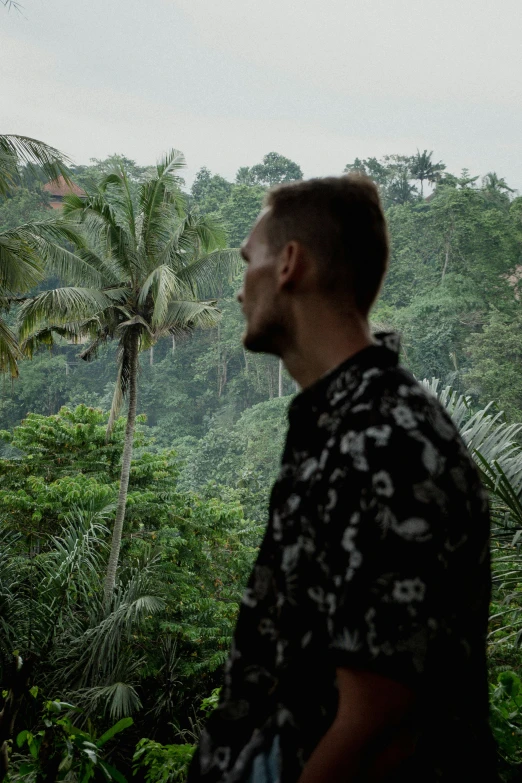 a man in an image of tropical rainforest, staring off to the left