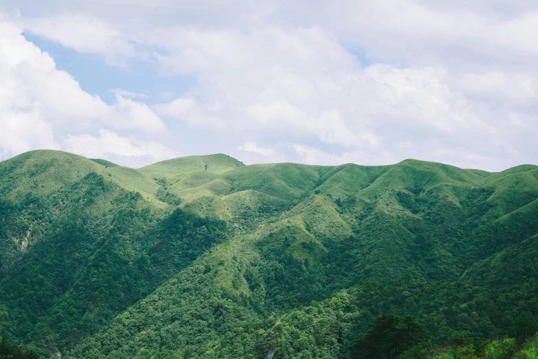 the mountains are covered in green bushes on a cloudy day