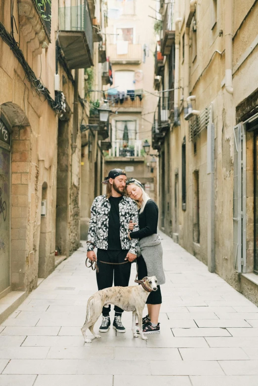 couple and two dogs standing on side walk in city