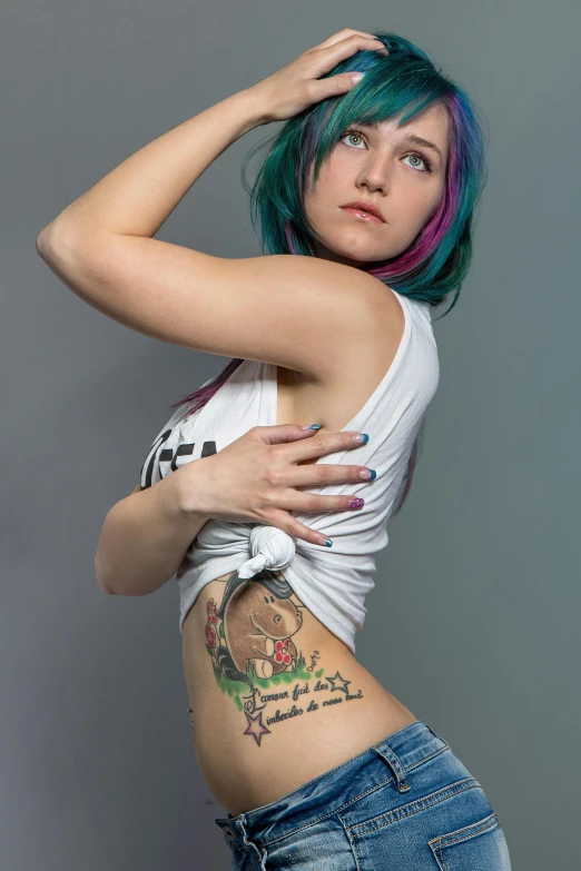 a young woman with tattoos standing next to wall